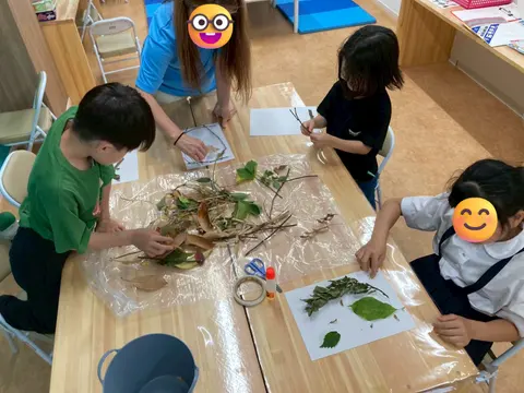 葉や枝を使った自然工作に取り組む子どもたちと先生