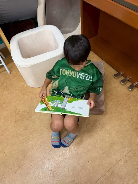 絵本を膝に広げて読む男の子