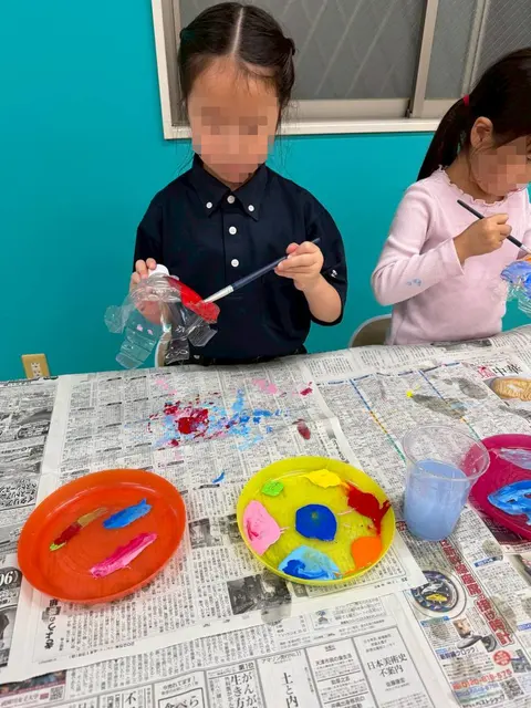 新聞紙を敷いて絵の具で工作をする子どもたち
