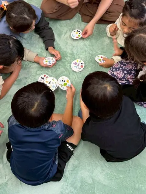 床に座って絵カードのゲームを楽しむ子どもたち