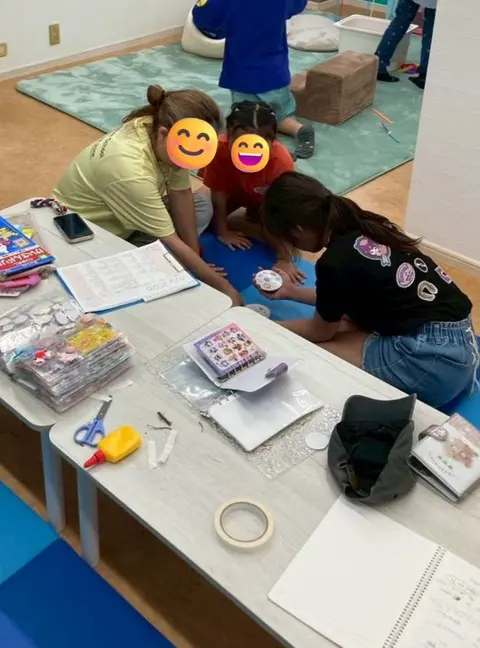 先生と一緒にシールやカードの工作を楽しむ子どもたち