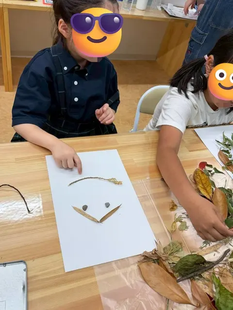 葉や小枝で顔の形を作る自然アートに取り組む子ども