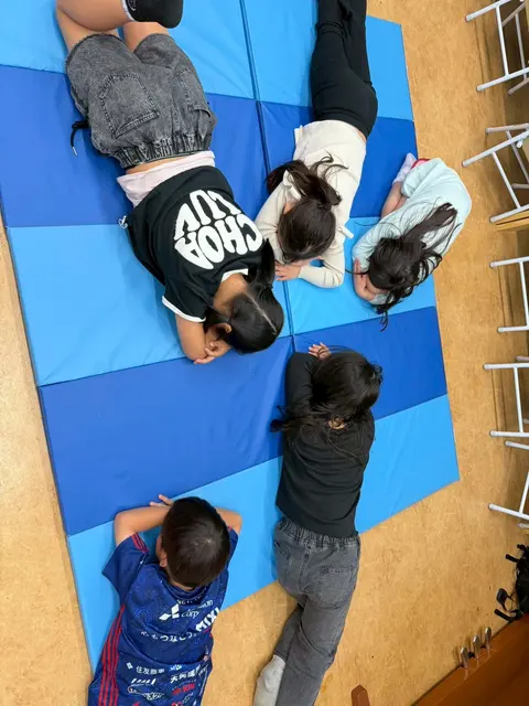 青いマットの上に寝転んで遊ぶ子どもたち