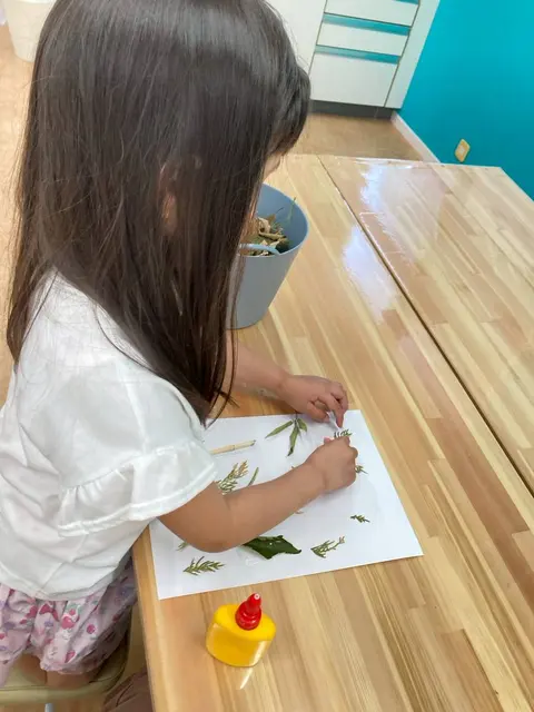 葉っぱを紙に貼って自然工作をする女の子