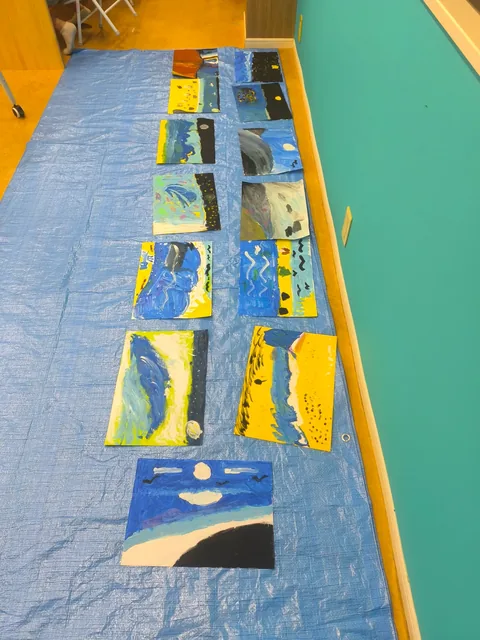 子どもたちが描いた海の絵が並ぶ教室の床