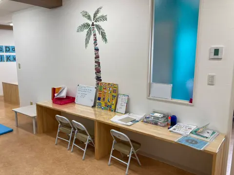 ヤシの木のウォールアートと学習用デスクがある教室