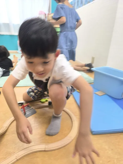 木製の電車のレールで遊ぶアフタースクールの子ども