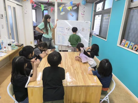 ホワイトボードの前で先生の話を聞くアフタースクールの子どもたち