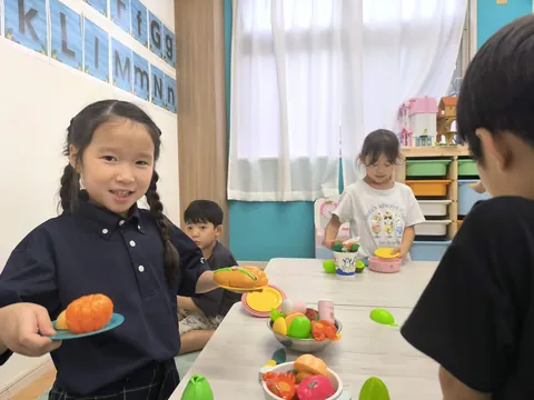 おもちゃの食べ物をお皿にのせて見せてくれるアフタースクールの子ども