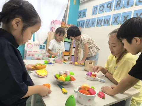 先生と一緒におままごとの料理を作るアフタースクールの子どもたち