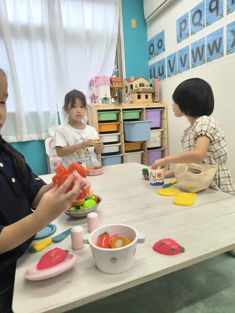 おもちゃのカニを手におままごとをするアフタースクールの子ども