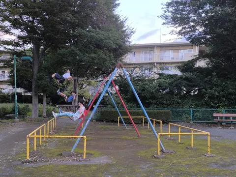 放課後に公園で並んでブランコをこぐ子どもたち