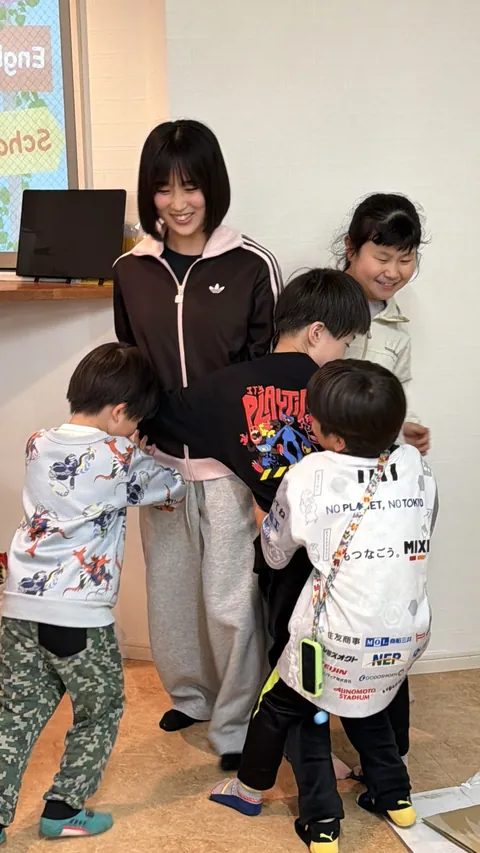 アフタースクールで先生を囲んで笑顔を見せる子どもたち