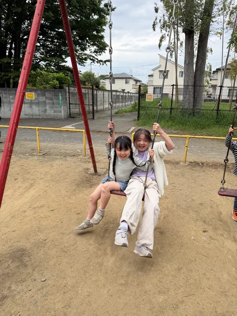 公園でブランコに乗って笑顔を見せる子どもたち