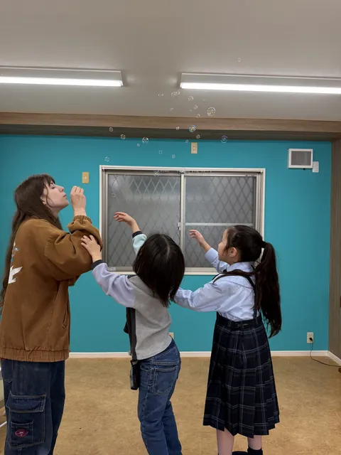 先生と一緒にシャボン玉を追いかける子どもたち