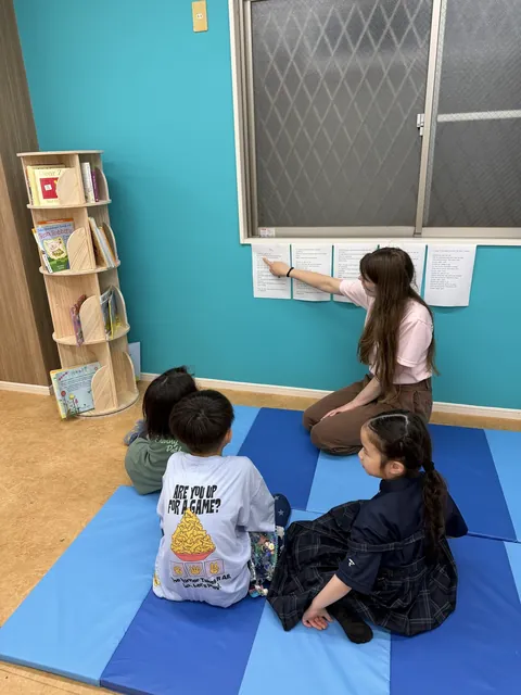先生が指さす英語の掲示を見る子どもたち