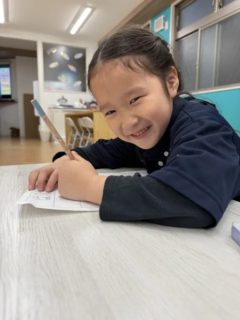 英語のプリントに取り組みながら笑顔を見せる女の子