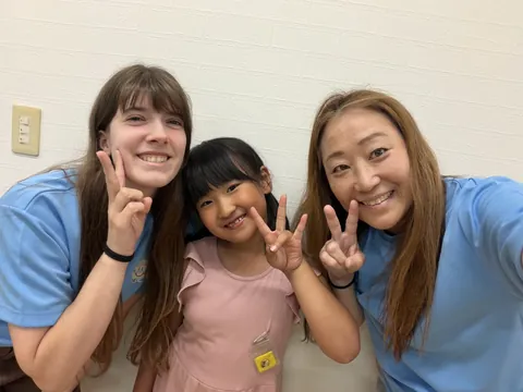 先生たちと一緒にピースをする女の子
