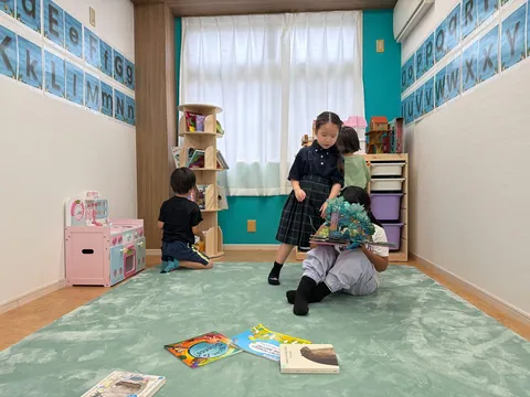本棚のそばで英語の絵本を楽しむ子どもたち