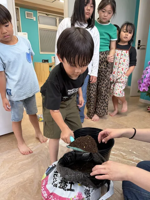 鉢植えの土入れをする子どもたち