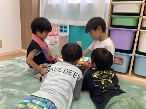 マットの上で頭を寄せ合って遊ぶ子どもたち
