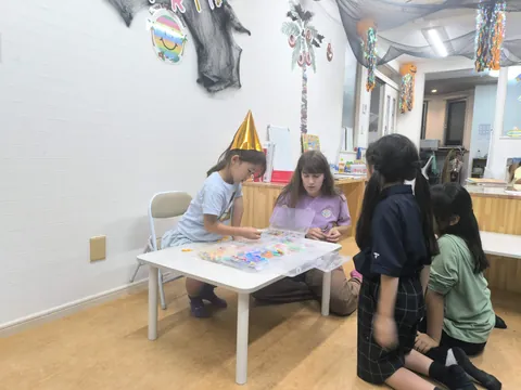 アフタースクールのお誕生日会で、先生と一緒にビーズのアクセサリーを作る子どもたち