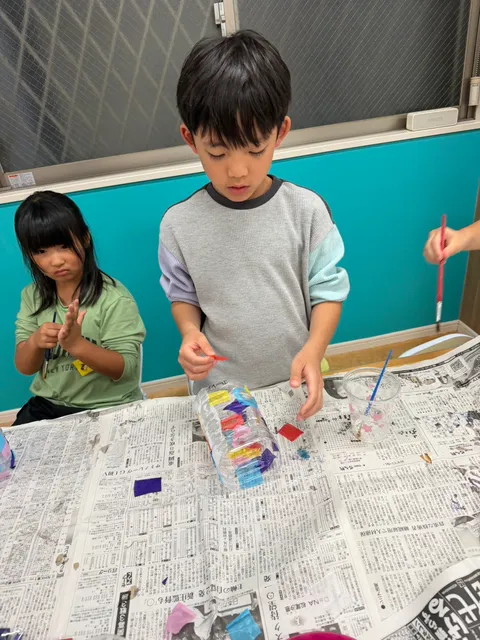 ペットボトルに色紙を一枚ずつ貼ってランタンを作る男の子