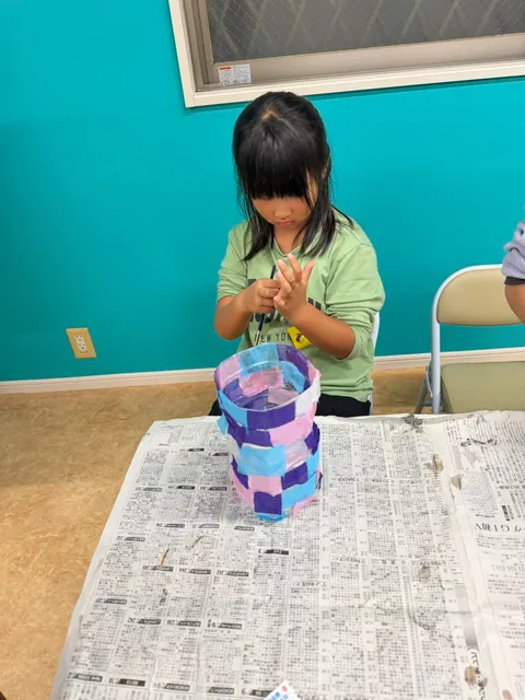 紫・ピンク・水色の紙で仕上げたランタンを前にする女の子