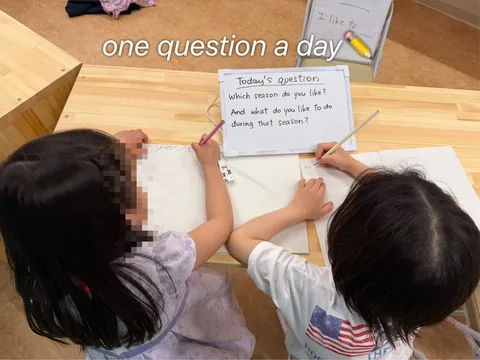 「One Question A Day」の英語の質問に答えを書くアフタースクールの子どもたち