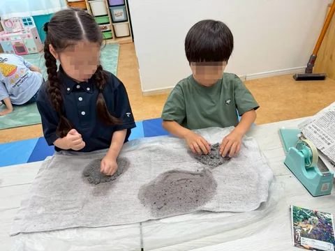 粘土のような素材を手でこねて工作するアフタースクールの子どもたち