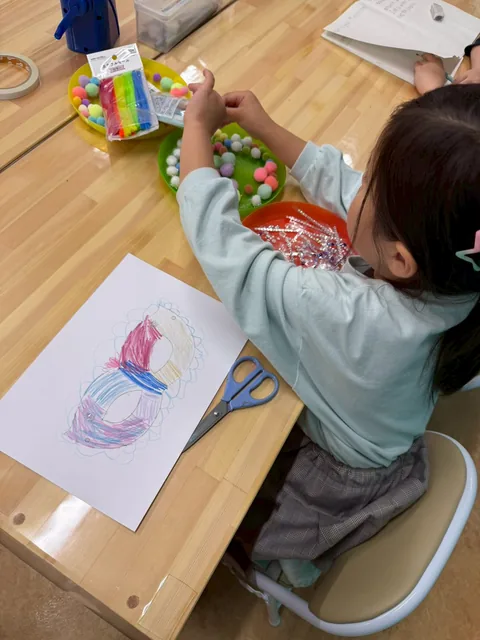 机でクレヨンと色鉛筆を使って絵を描くアフタースクールの子ども