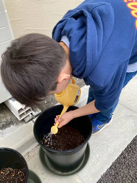 じょうろで土に水をあげるアフタースクールの男の子