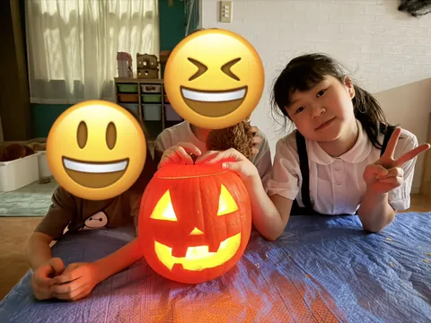明かりのついたジャック・オー・ランタンを囲んでピースをする子どもたち