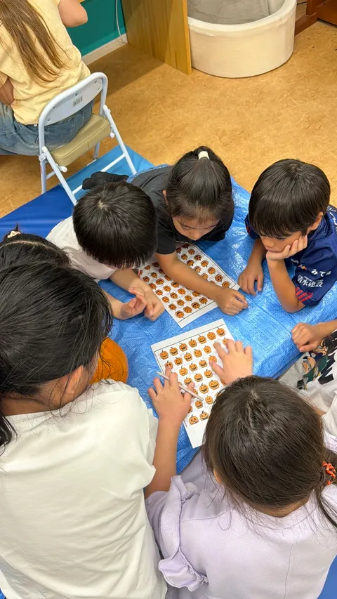 見本シートを見比べながら、かぼちゃに描く顔を選ぶアフタースクールの子どもたち