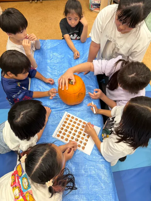 顔を描いたかぼちゃと見本シートを囲んで話し合う子どもたち
