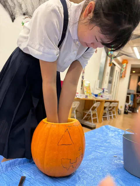 両手をかぼちゃの中に入れて中身をかき出す女の子