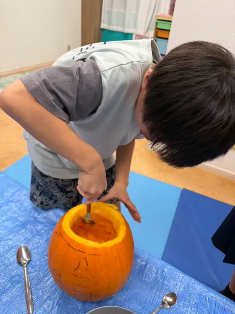 スプーンでかぼちゃの内側をきれいにくり抜く男の子