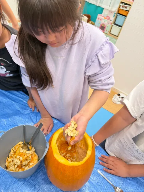 かぼちゃから取り出した種を手のひらいっぱいに持つ女の子