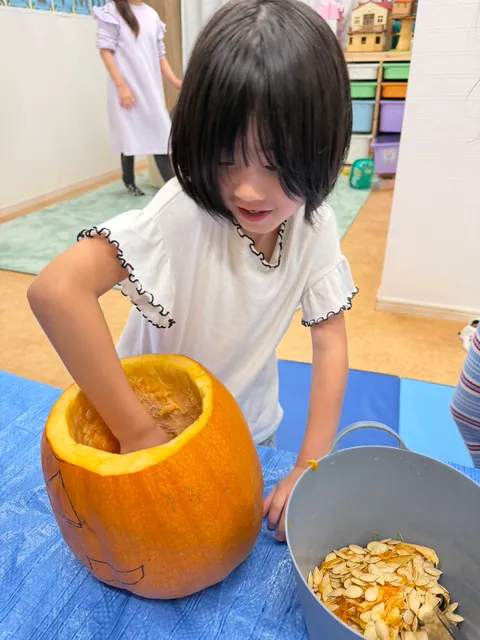 笑顔でかぼちゃの中身をかき出す女の子