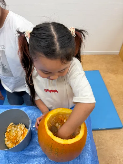 かぼちゃの中に腕を入れて中身を取り出す女の子