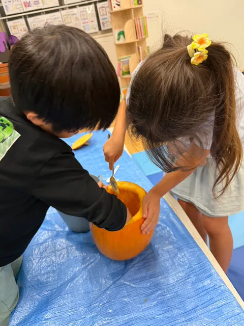 二人で協力してスプーンでかぼちゃの中をきれいにする子どもたち