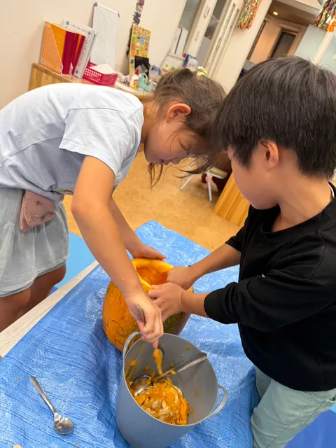 かぼちゃの中身をスプーンでボウルに移す子どもたち
