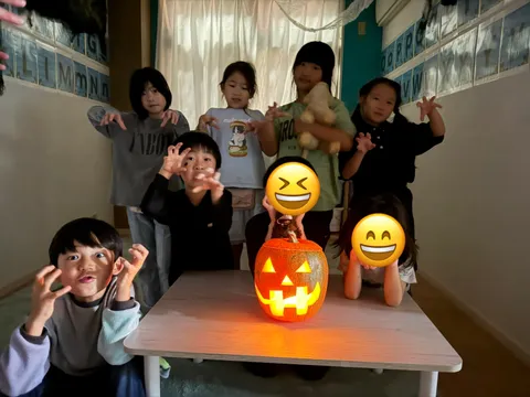 明かりのともったジャック・オー・ランタンを囲んで、おばけのポーズをする子どもたち