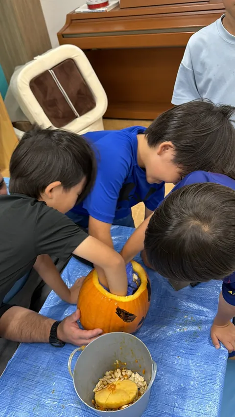 アフタースクールのハロウィンで、みんなでかぼちゃの中身をかき出す子どもたち