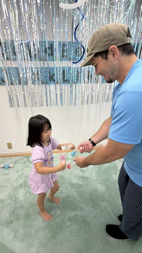 キンダースクールで先生と一緒に体を動かして遊ぶ子ども