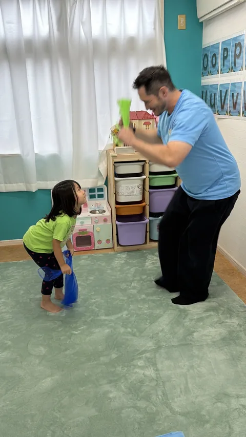 キンダースクールで先生と体を動かして遊ぶ子ども