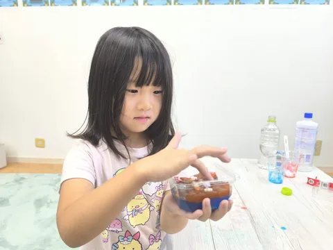 キンダースクールで手作りのゼリーを見せる子ども