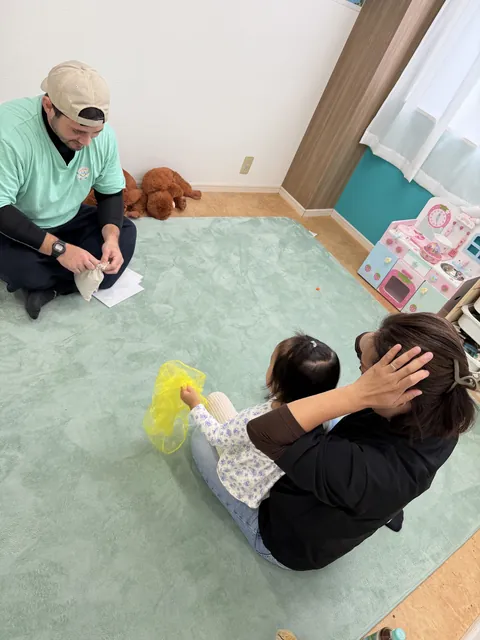 黄色いスカーフを持って先生と手遊びをする親子