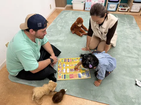英語のカレンダーで曜日や月を学ぶ女の子とお母さんと先生