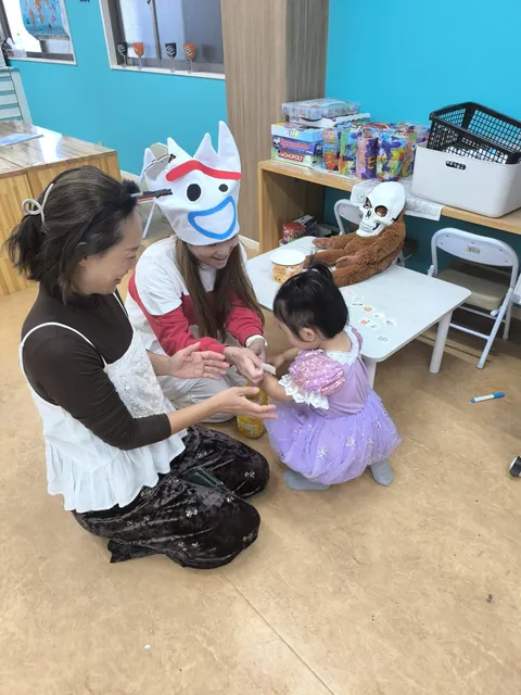 ピーカブーのハロウィンで、タトゥーシールを貼ってもらって笑顔のお母さんと先生